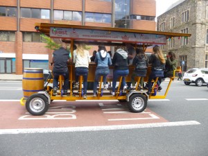 What is this coming along Great Victoria Street?  A sort of caterpillar driven by a dozen people peddling away to make the wheels on the bus go round and round as the music issues forth.  Happy day in Belfast.